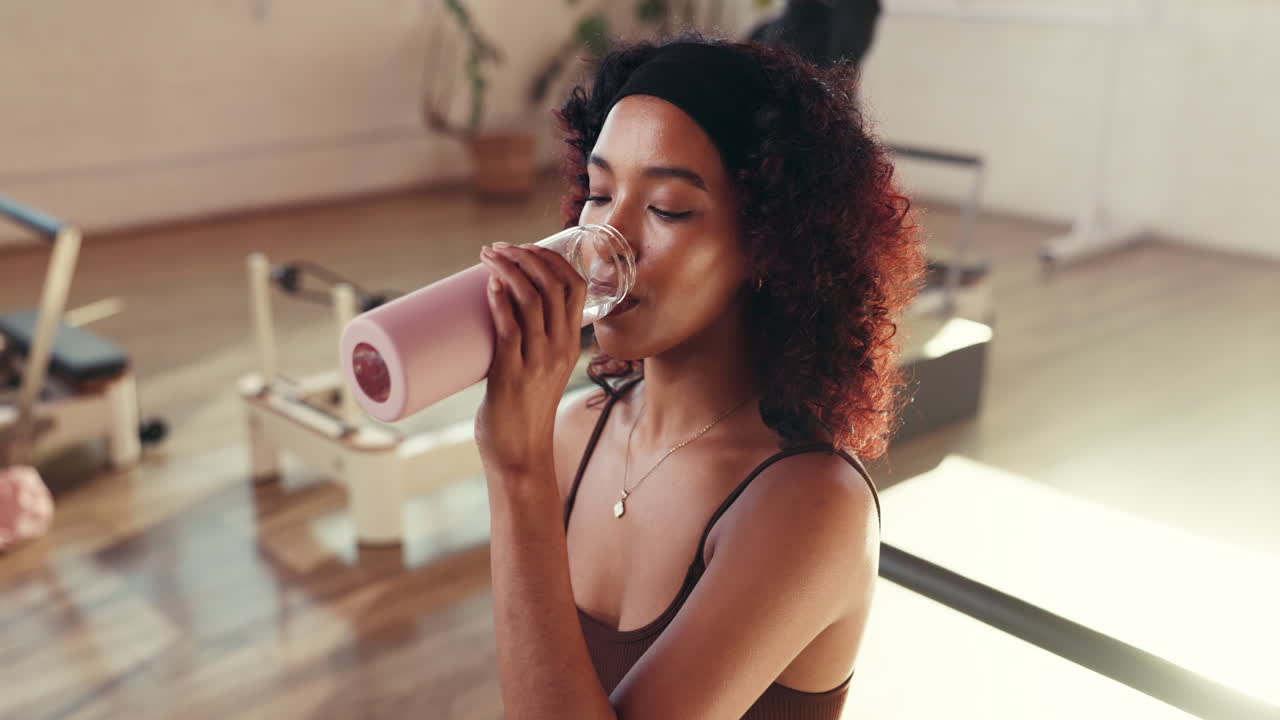 Woman drinking water after pilates workout