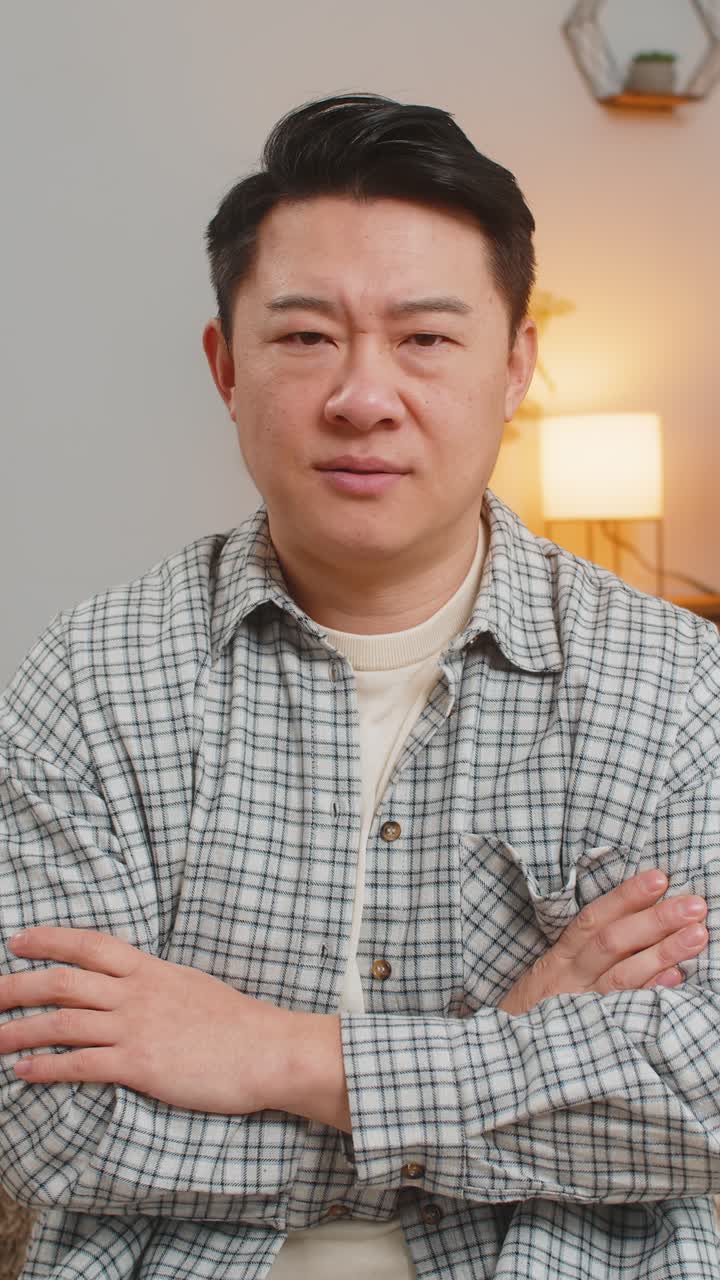 Upset man showing thumbs down sign gesture expressing discontent sitting on sofa couch at home