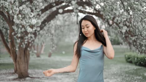 woman in blue dress among blooming trees