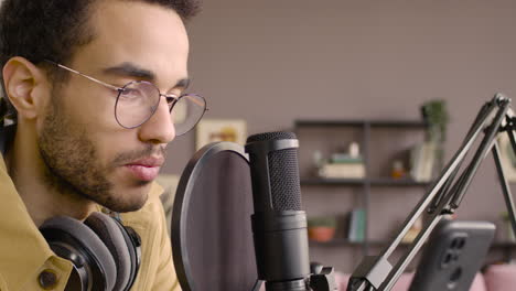 close up view of man recording a podcast wearing eyeglasses and headphones