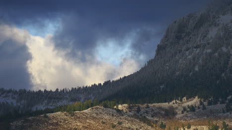 montañas boscosas cubiertas de nieve contra la puesta de sol con cielo nublado