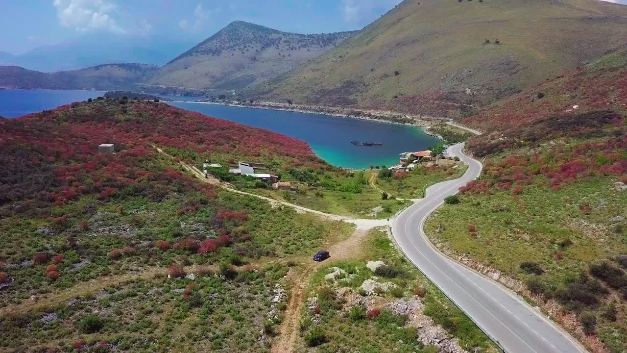 동부 유럽의 알바니아 리비에라에 있는 포르토 팔레르모의 장엄한 해안 도로를 따라 여행하는 검은색 자동차
