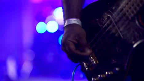 bass guitar is being played at a concert with lights flashing in the background