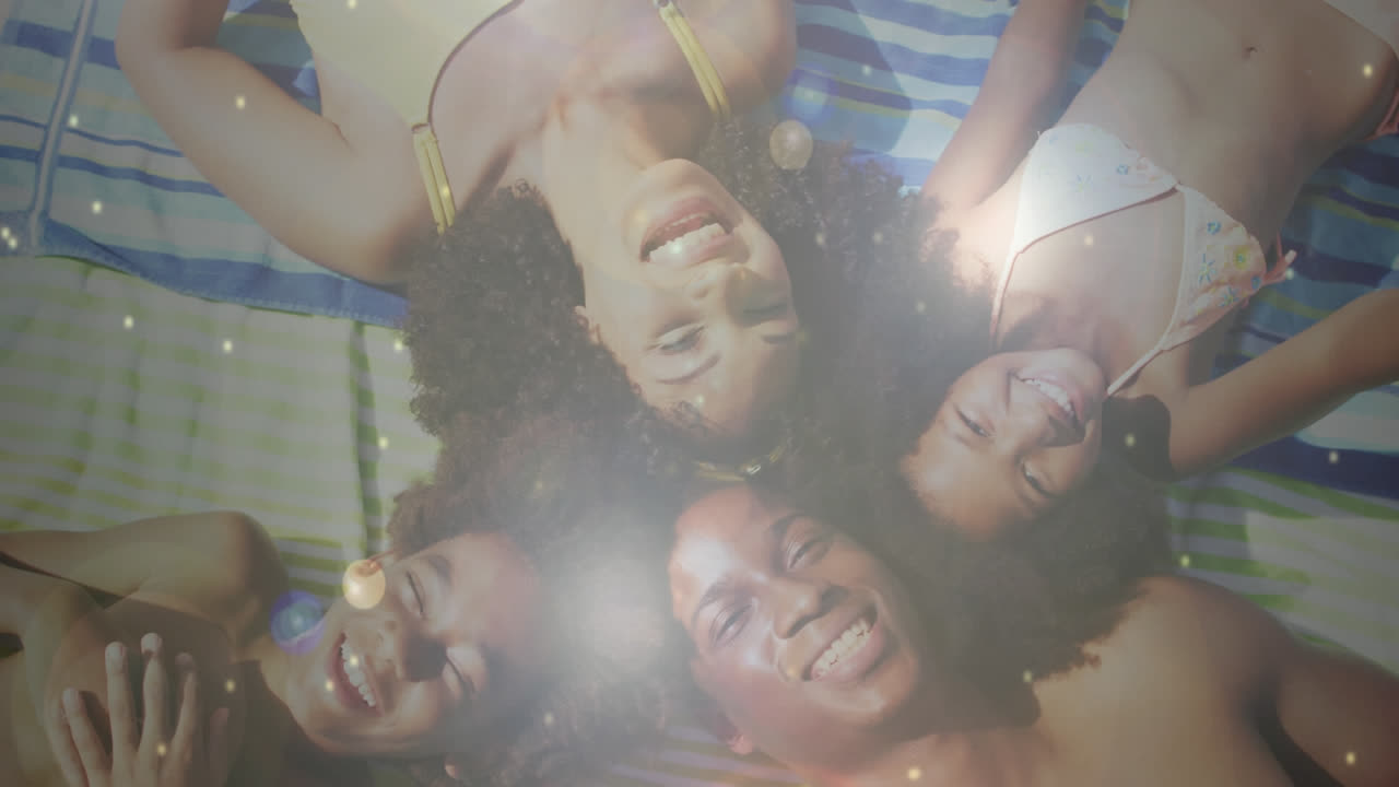Composite of sunlight and lens flare over happy african american family lying on beach waving