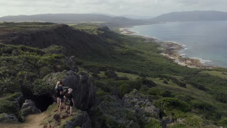 group of hikers looking at the kenting national park view on a sunny day in taiwan - aerial shot