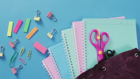 video of school supplies, notebook, pens, marker pen and notebooks over blue background