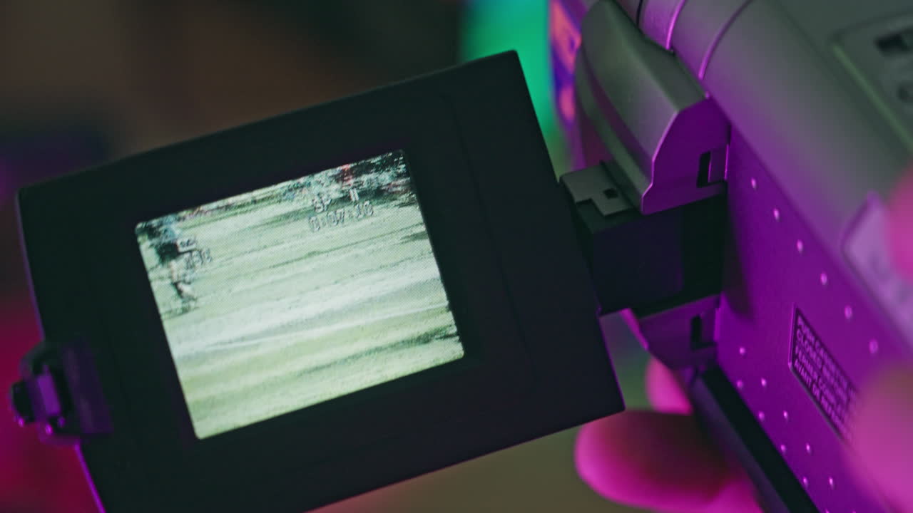 Close-Up of Hand Holding Retro Camcorder with Blue Screen
