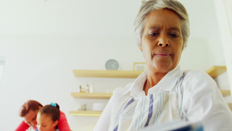 abuela leyendo el libro de recetas en la cocina 4k
