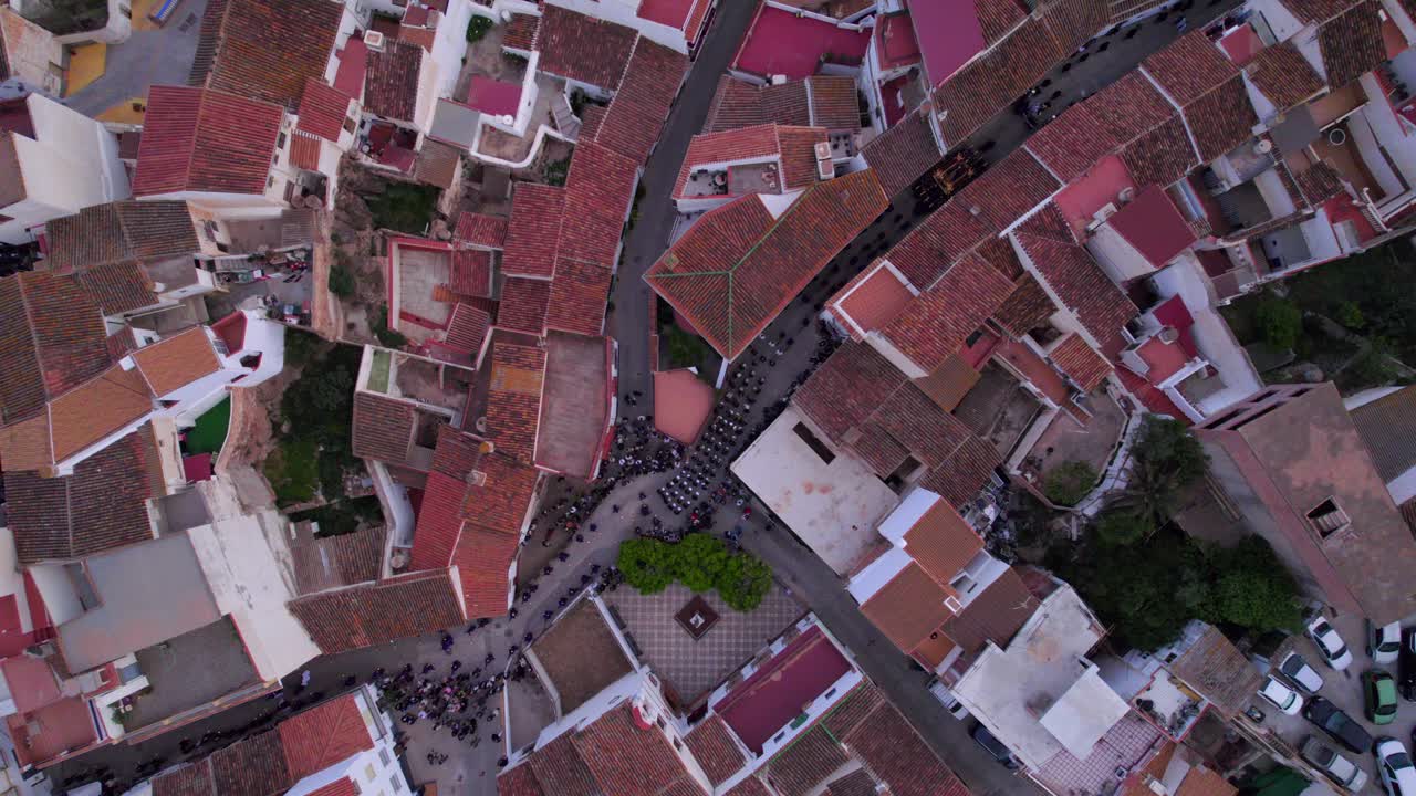 스페인 마을 의 거리 를  ⁇ 고 있는 사람 들 이 전형적 인 그리스도인 부활절 행진 을 하고 있는 공중 에서 아래 로 내려다보는 모습