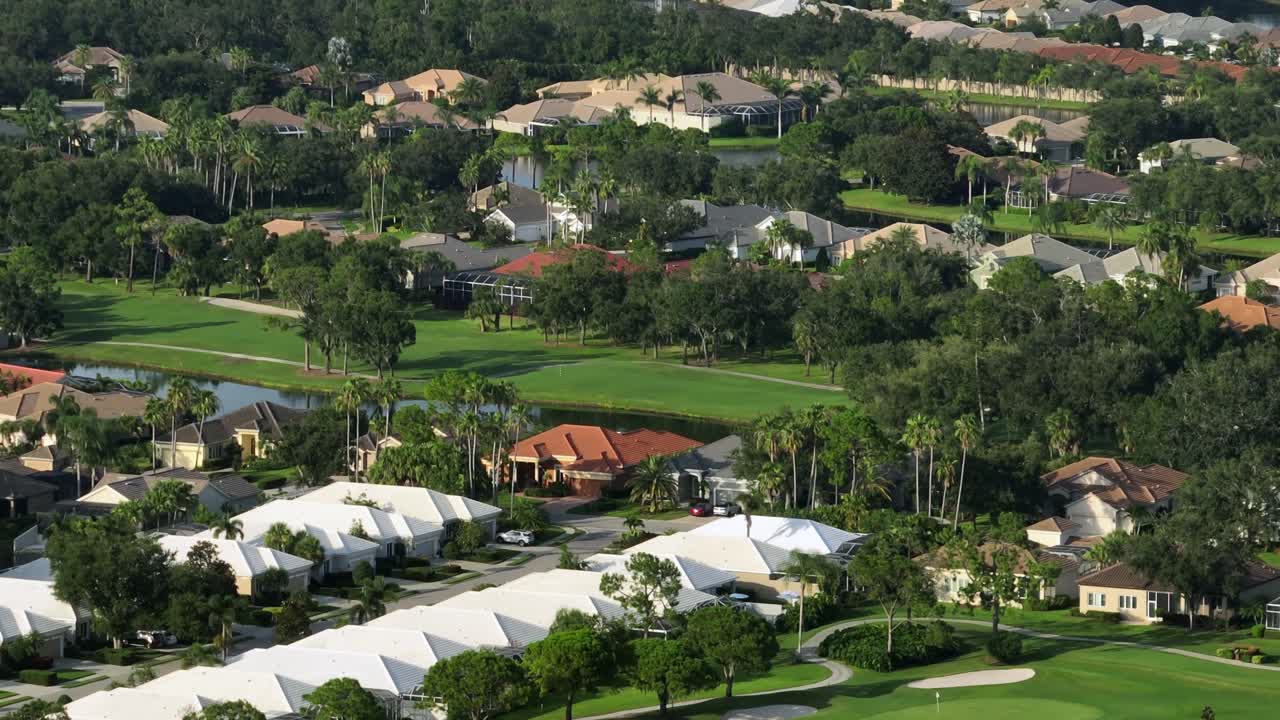 Lake, well-maintained golf course and luxury houses in golf club of Brandenton, Florida. Sunset time. Aerial wide shot. Expensive housing area in America