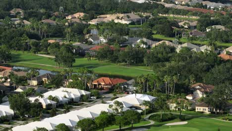 lake, well-maintained golf course and luxury houses in golf club of brandenton, florida. sunset time. aerial wide shot. expensive housing area in america