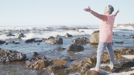 senior african american woman widening arms at beach, copy space, slow motion