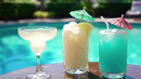 refreshing summer cocktails: a close-up of vibrant drinks by the poolside with colorful umbrellas and ice in a tropical paradise setting