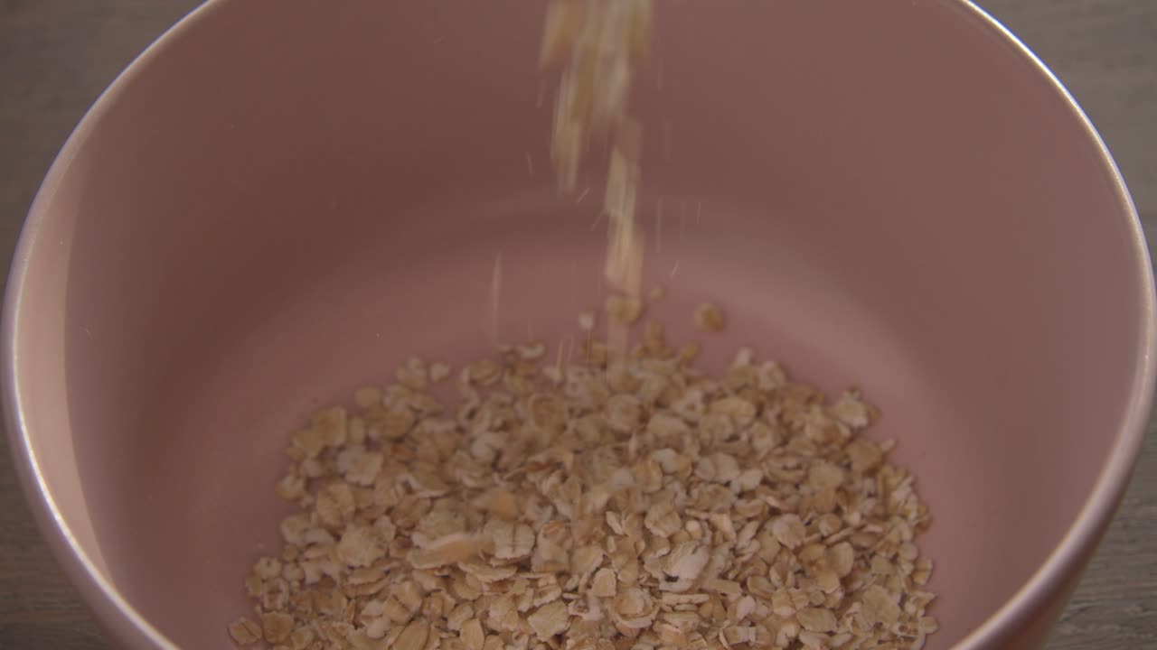 아침 식사로 분홍색 그릇에 건강한 시리얼을 붓는다