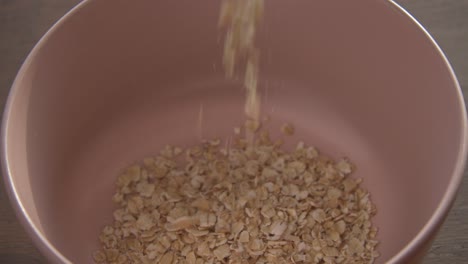 pouring of healthy cereals in a pink bowl for breakfast