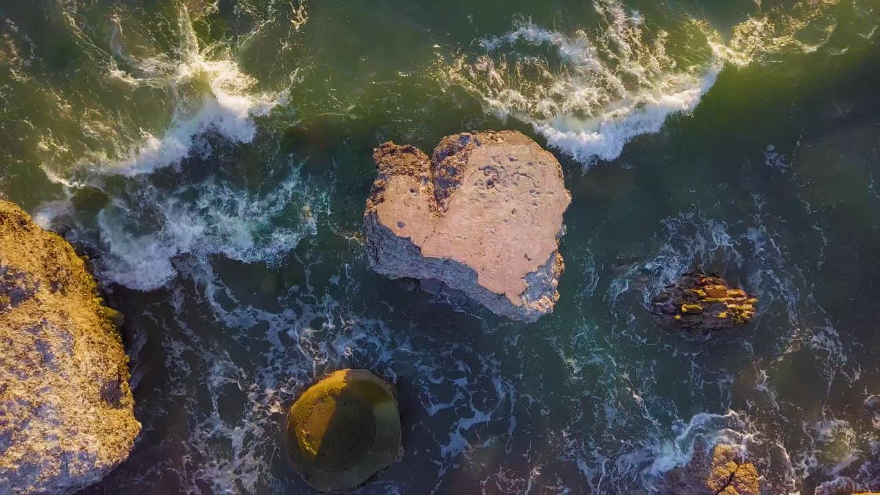 vista aérea de los edificios de fortificación costeros abandonados en los fuertes del norte de karosta en la playa del mar báltico, salpicaduras de olas, puesta de sol de la hora dorada, tiro de carro de drones moviéndose a la izquierda