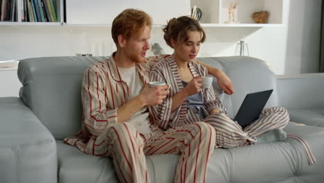 husband embracing wife surfing internet together. romantic couple drink coffee