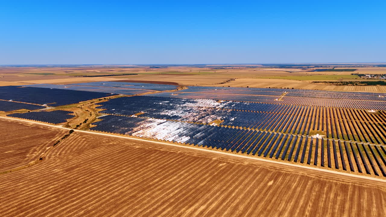 Large solar power plant in open landscape. Aerial view of a huge solar power plant with thousands of photovoltaic panels under clear blue sky