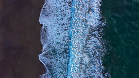 drone top view of turquoise ocean waves crashing ashore