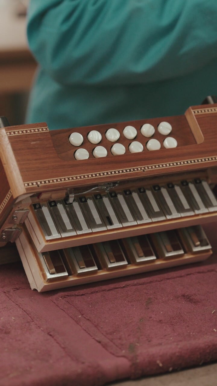 Detailed view of concertina keyboard buttons and internal reeds exposed during repair process in Portugal workshop vertical framing