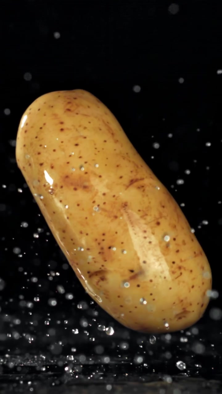 Patata fresca che schizza nell'acqua su sfondo nero