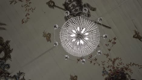 Elegant crystal chandelier hanging from a beautifully painted ceiling with intricate designs