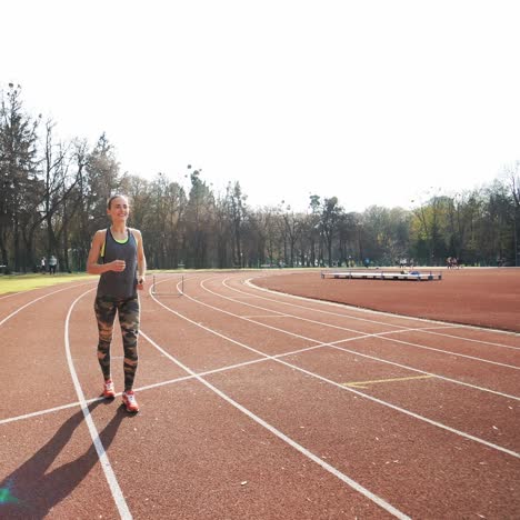 frau bereitet sich darauf vor, auf dem stadion zu starten - sommer-außen-training. athletische frau läuft auf der strecke.