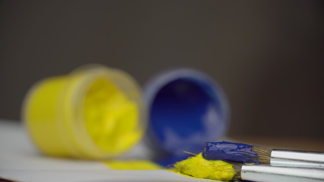 toman pintura amarilla y azul con un pincel, ucrania