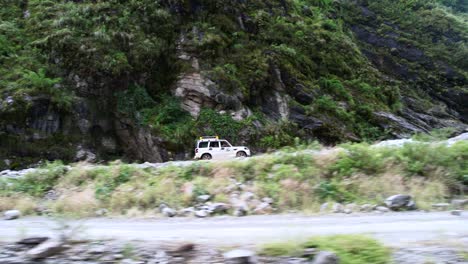 aerial tracking shot of a off road jeep driving tourists up a dangerous rugged mountain road to jomsom nepal