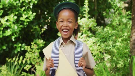 Animation-of-african-american-girl-in-scout-costume-smiling-at-camera-in-garden