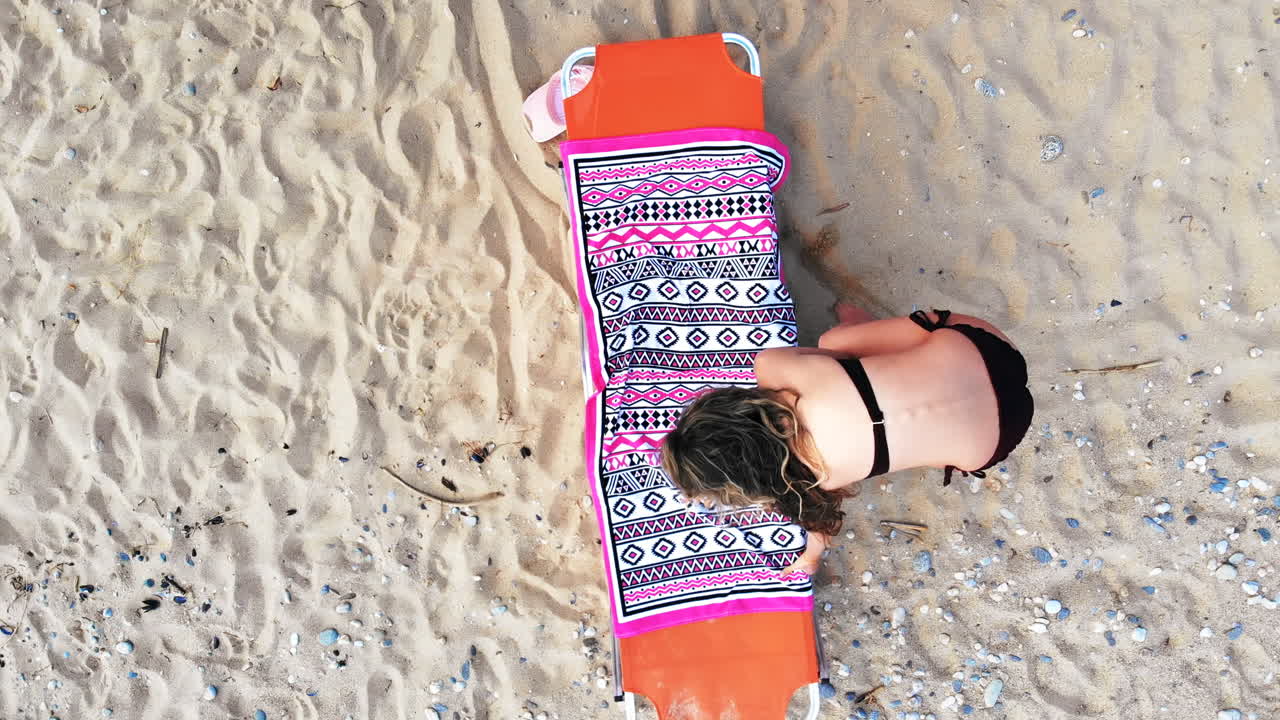 Top view of a woman laying on sunbed, relaxing and looking up