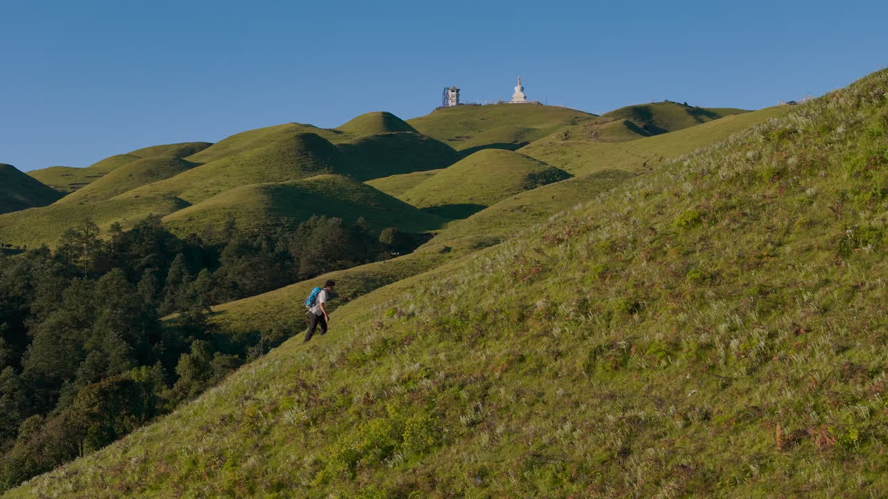 Drone shot of male hiker in Nepal trekking through green hills and forested mountain landscape of Sailung Dolakha lush scenery and serene environment cinematic adventure tourism near Tibet border