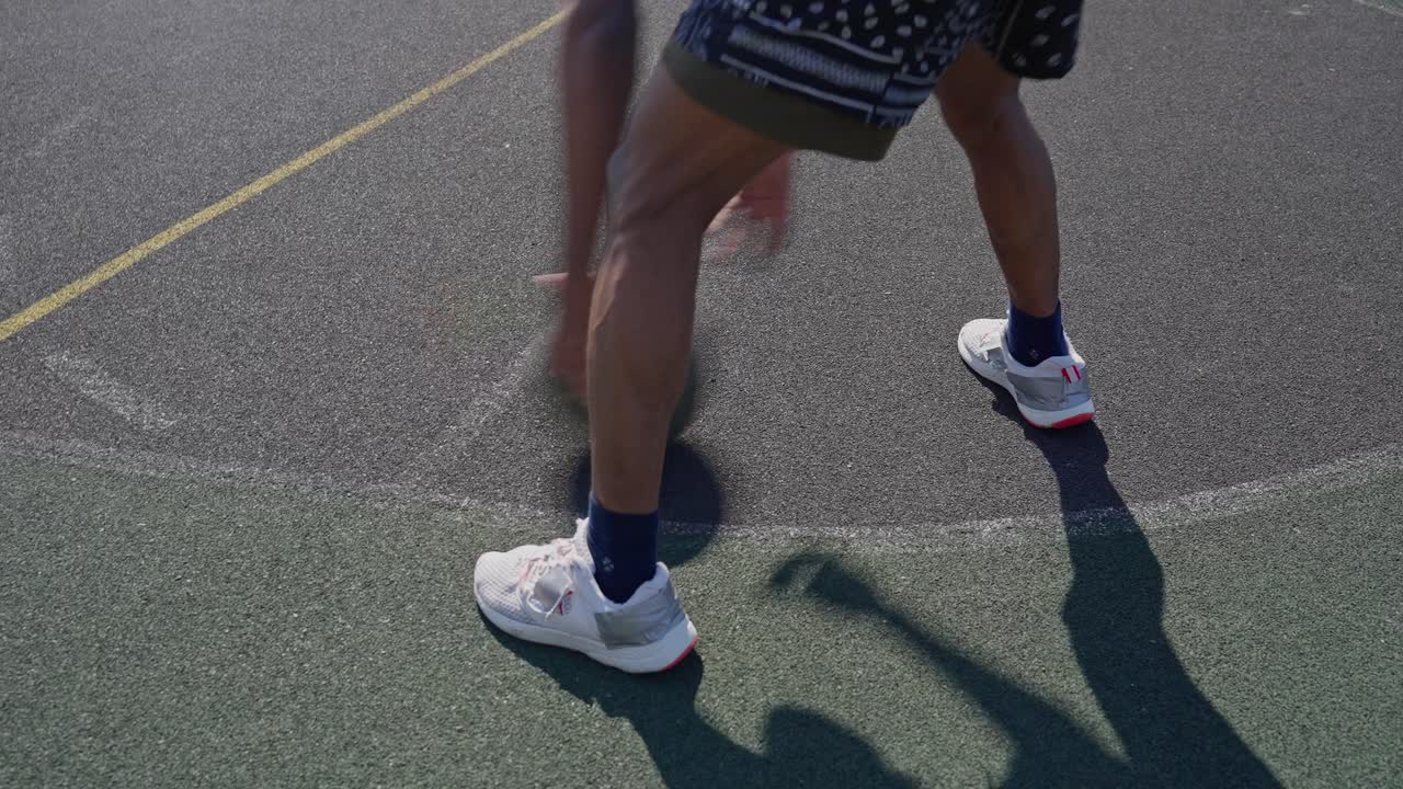 Primer plano de una persona botando un balón de baloncesto en una cancha al aire libre
