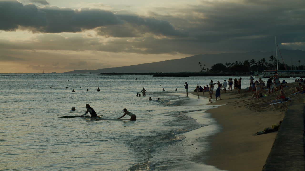 People swimming and enjoying a beach at sunset