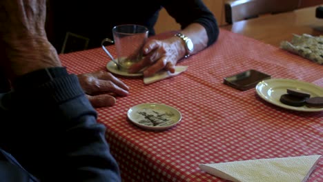 Close-up-of-a-senior-couple-chatting-and-having-a-cup-of-tea-with-cookies-on-a-kitchen-table