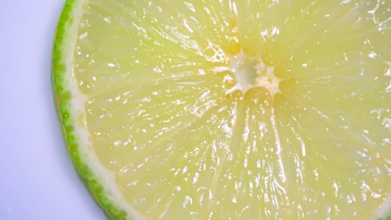 una rebanada de limón verde está girando lentamente en el estudio con los detalles.