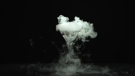 drink in glass of martinis with the effect of dry ice - drink in glass of martinis with the effect of dry ice on black background at studio. closeup