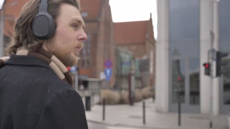 stylish guy in scarf and coat listen a music on streaming service by using mobile phone