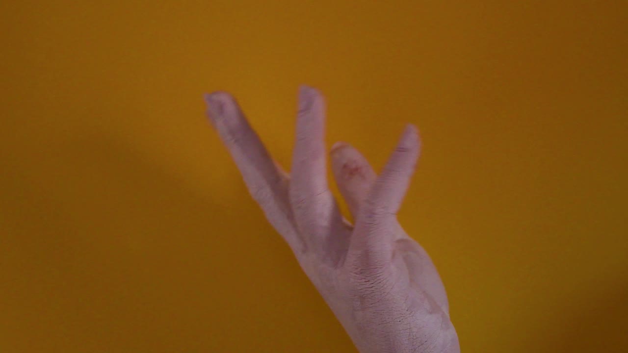 молодая женщина, нарисованная белой краской, плавно движется на желтом фоне