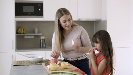 cheerful mom and little daughter cutting fresh apples