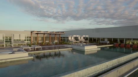 pan shot of a modern building with a luxurious rooftop terrace with a pool at dusk