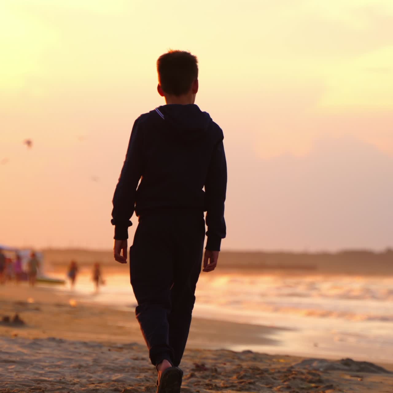 Boy walking at beach on sunset