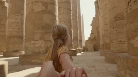 follow me to egypt: young couple holding hands wile sightseeing ancient egyptian temple.