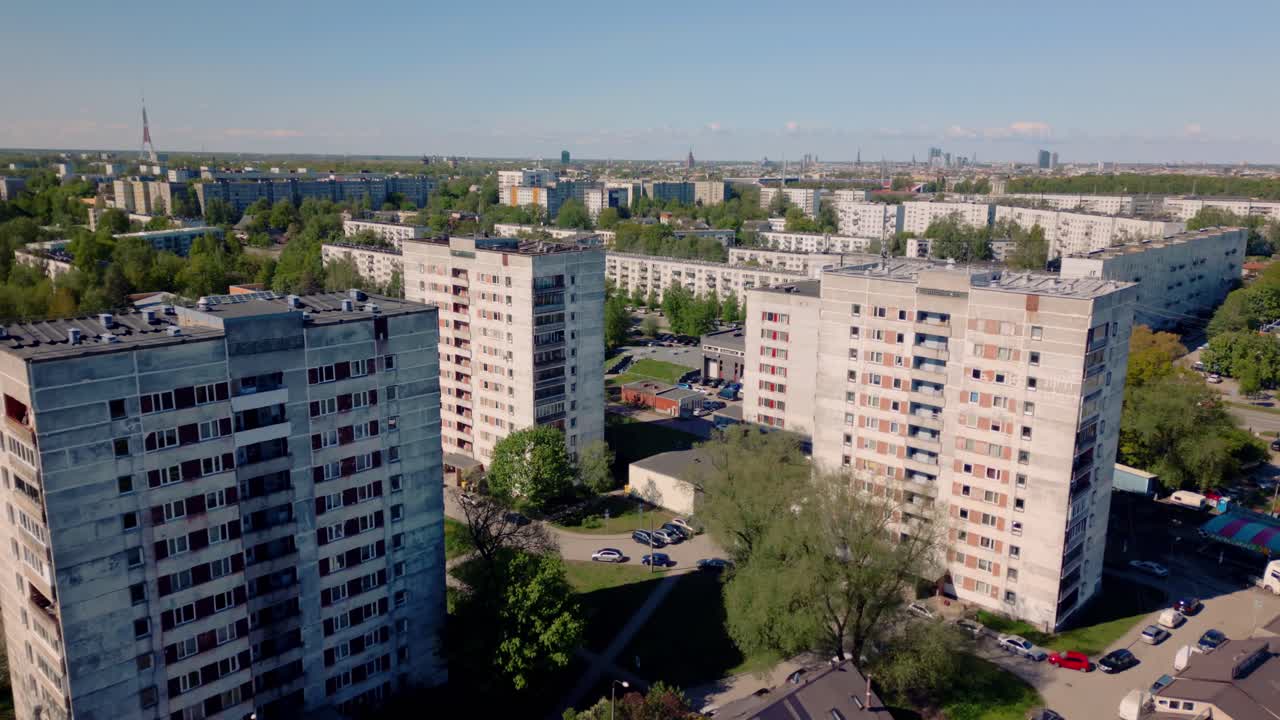 Aerial drone footage of Soviet-era apartment blocks in Riga's Purvciems suburb, showcasing the dense layout, concrete structures, and green spaces