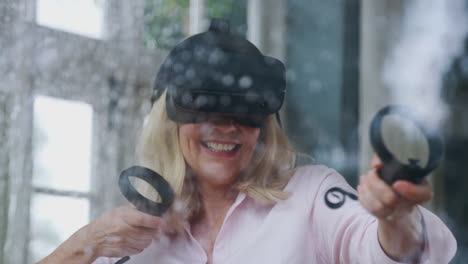 view through window as mature woman wears virtual reality headset and holds gaming controllers