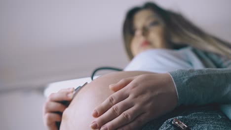 pregnant-lady-uses-stethoscope-to-examine-baby-close-view