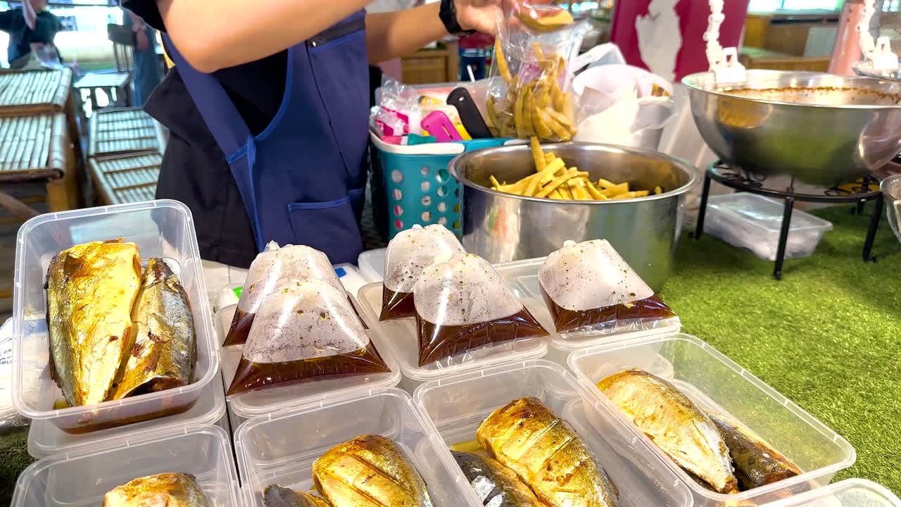 vendedor prepara platos de pescado en el mercado de bangkok