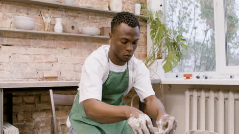 american clerk modeling ceramic piece on a potter wheel in a workshop