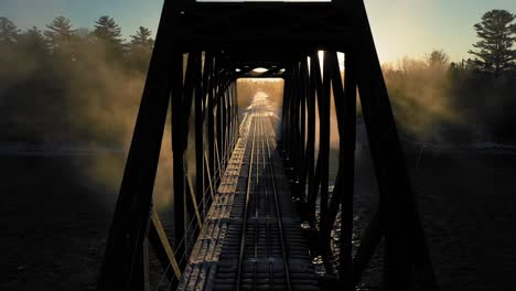 Grúa-Aérea-Arriba-De-Un-Caballete-De-Ferrocarril-Retroiluminado-Con-El-Amanecer-De-Invierno-Parpadeando-En-Un-Exterior-Aunque-La-Criba-Del-Caballete