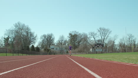 teen girl athlete running track towards and past camera in slow motion on a pretty day